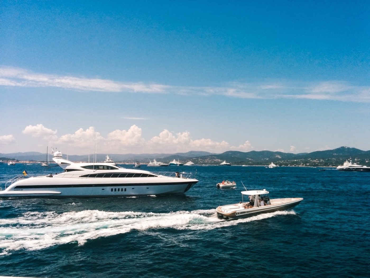 A motor yacht cruising with its tender in a Mediterranean bay