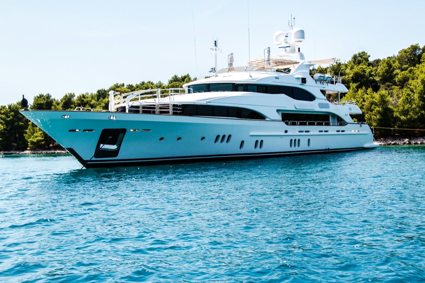 A white motor yacht photographed side-on against calm blue water